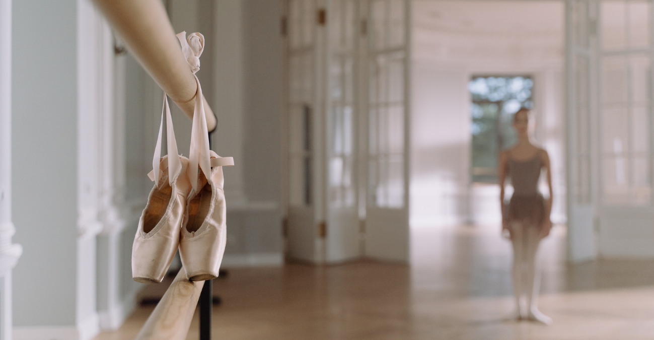 Pointe shoes hanging from a ballet barre in a dance studio